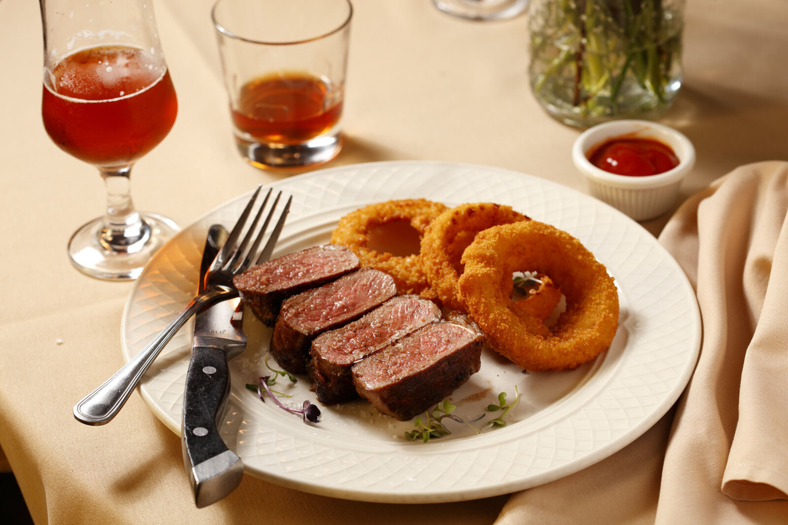 Sliced dry-aged strip steak with golden onion rings