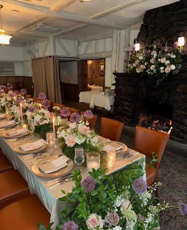 Floral-lined long table beside the stone fireplace