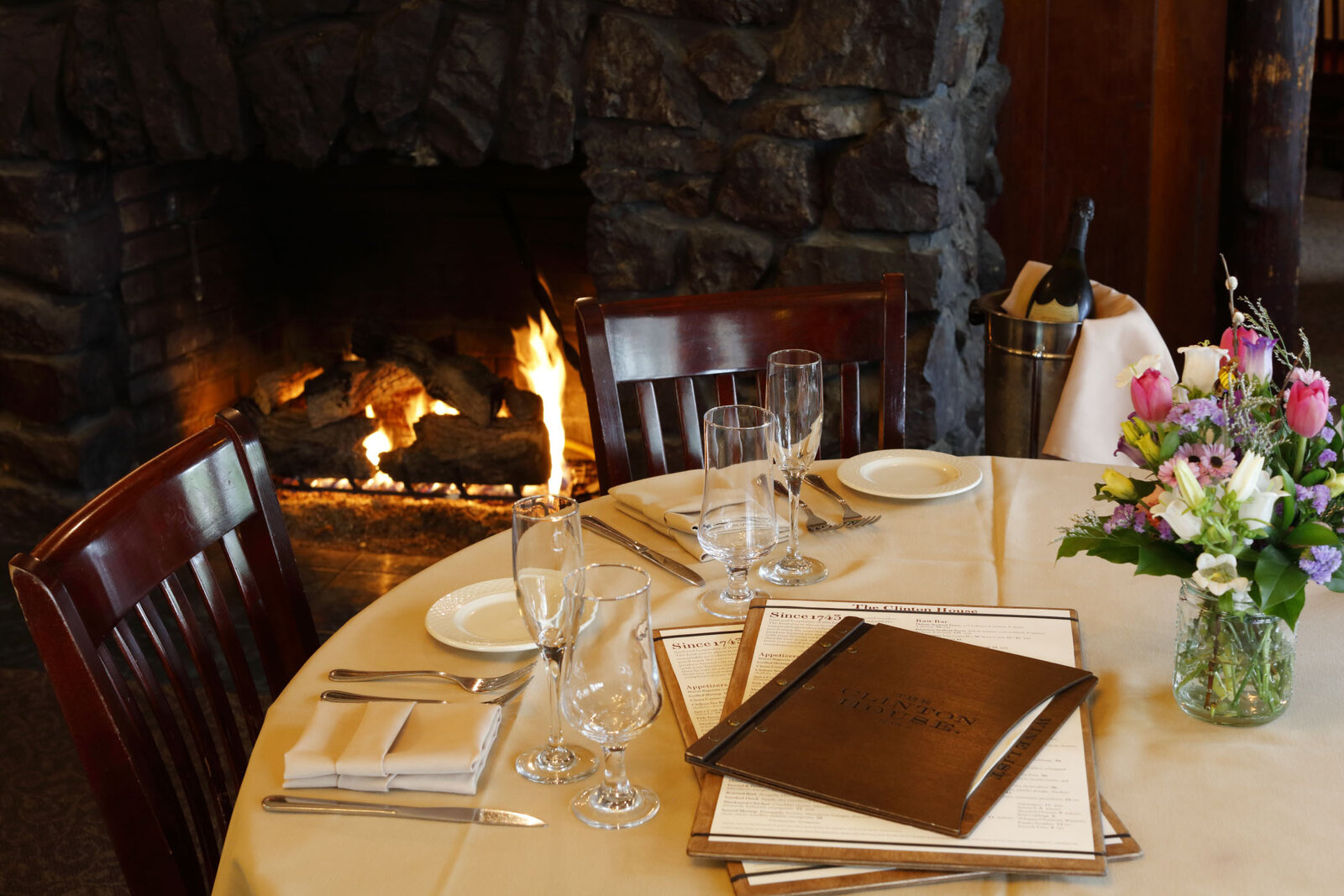 Dining room fireplace and table set with menus at The Clinton House