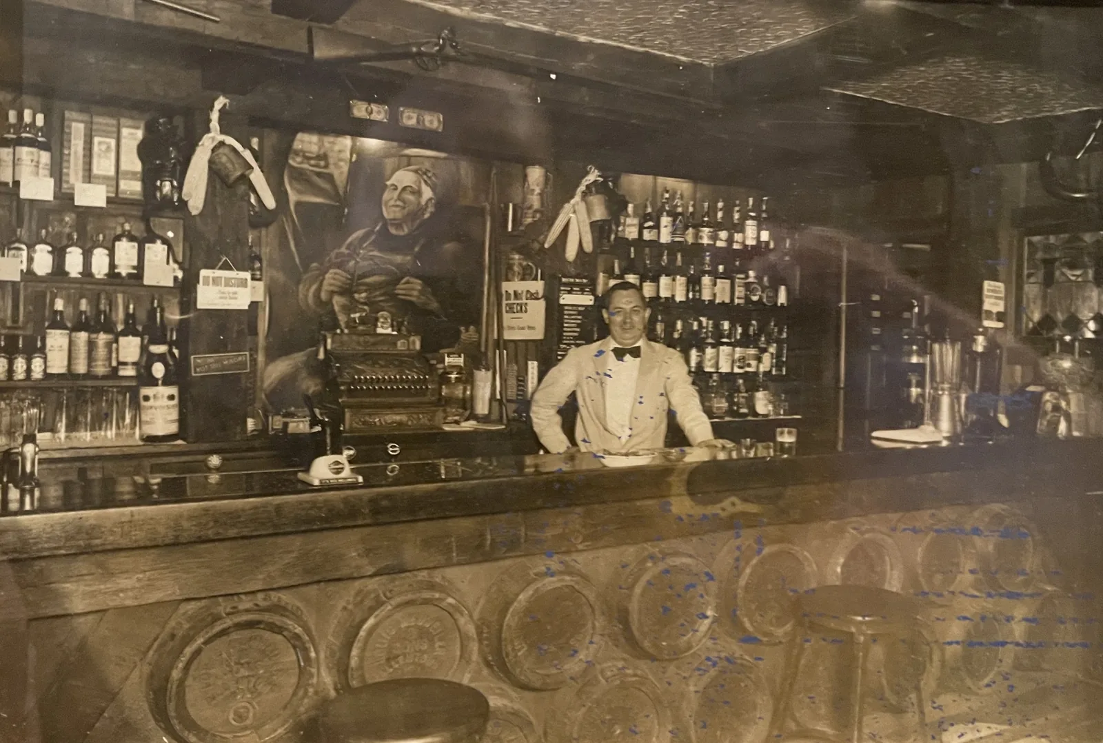 A bartender in white jacket and bow tie behind the Clinton House bar