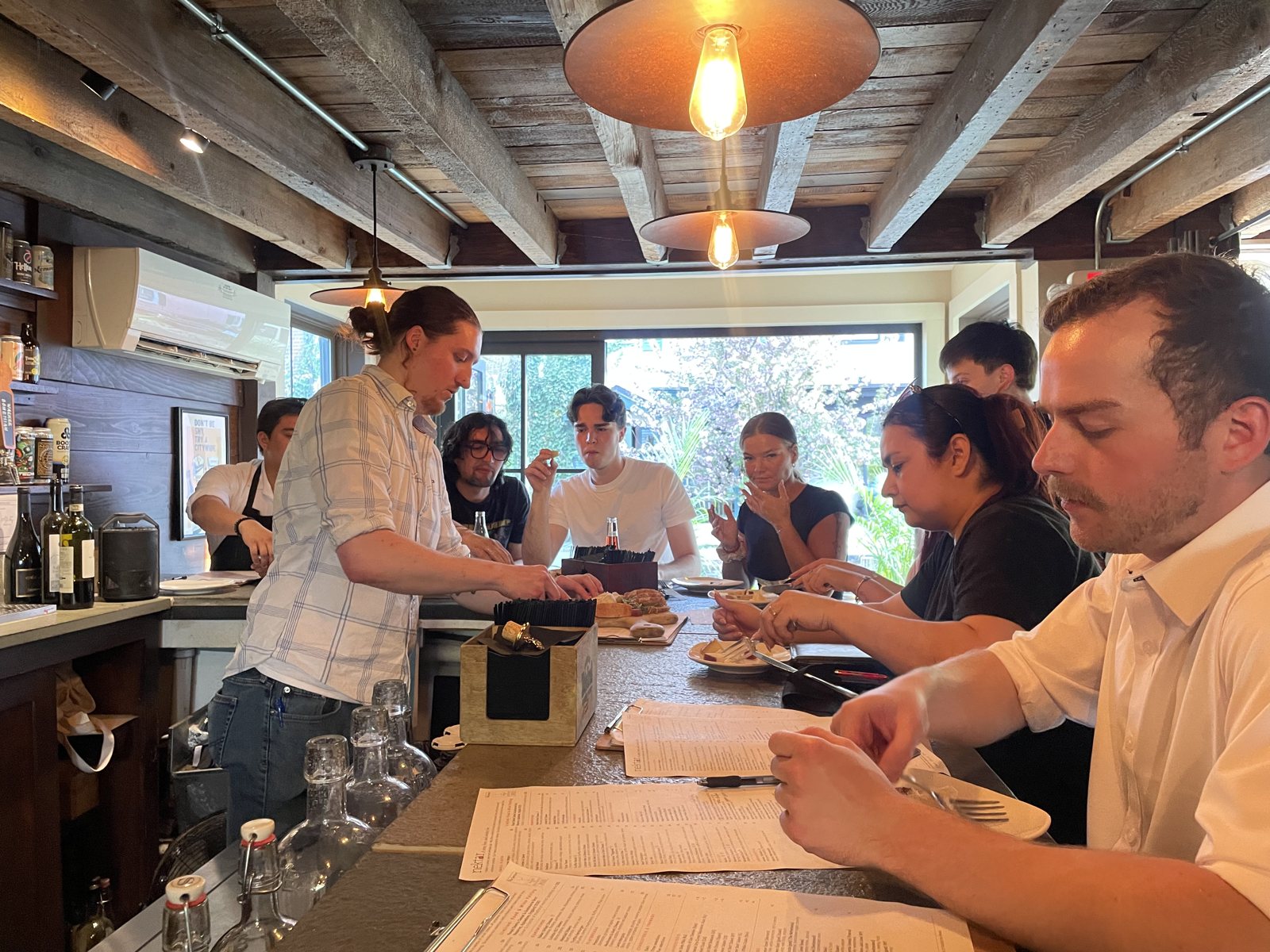 A manager leading a staff tasting and training at the bar.